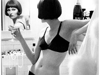 a1972-03-01 00.00.00  Model with champagne glass, looking over her shoulder into bathroom mirror; she's wearing a black bra and bikini with lace edging by Lorraine Lingerie : Fashion